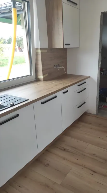 Kuchnia na wymiar z drewnianym blatem, panelem ściennym i okapem w zabudowie