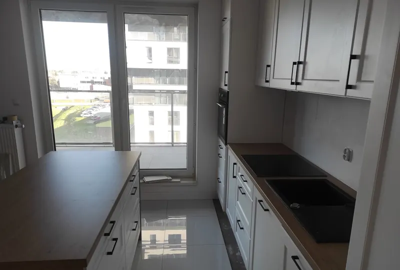 Kuchnia na wymiar z ciemnym blatem i wyspą ustawioną przy oknie